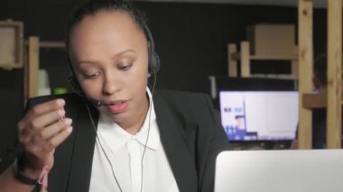 Kulaklığı olan Afrikalı Amerikalı bir kadının bilgisayar ekranına bakarken bir müşteriyle konuşmasını kapatın..