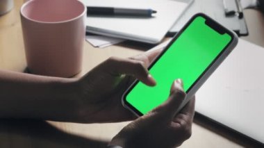 Genç Afrikalı Amerikalı kadın akıllı telefon kullanıyor. Cep telefonundan yeşil ekran izliyor.