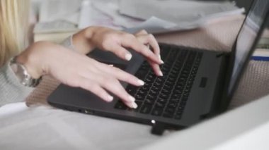 Yatağa uzanmış, not defterine yazı yazan bir kadın.