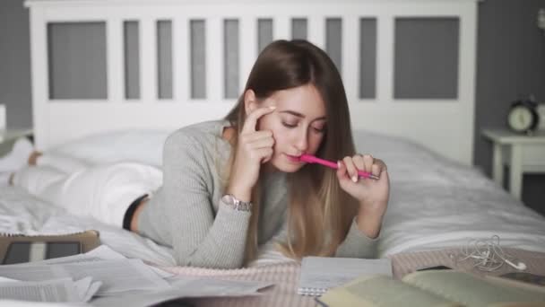 Молода жінка лежить на ліжку і вчиться — стокове відео