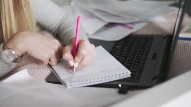 Close up of woman lying on the bed and making notes in notebook — Stock Video