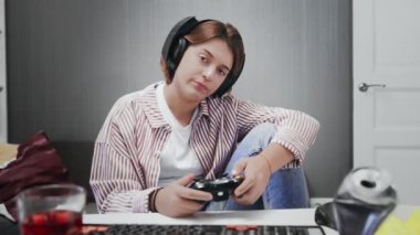 Sıkıcı Genç Oyuncu Kız bir kablosuz kontrolörle oyun konsolunda oynuyor.