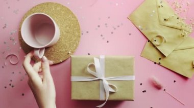 Ahşap pembe masanın en üst görüntüsü. El işi kağıt ve boş bardakta iki posta konseri var.