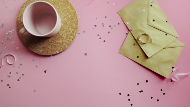 Manos de mujer dando un regalo de Navidad envuelto en papel artesanal con lazo blanco. Vista superior sobre tabla rosada de madera, posición plana — Vídeos de Stock