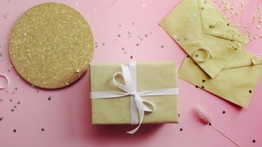 Ahşap pembe masa manzaralı, el işi kağıt ve bir fincan çay içinde iki posta konseri var.