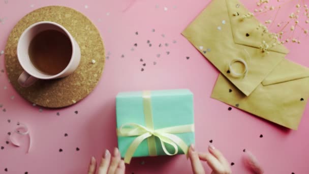녹색 종이에 싸인 크리스마스 선물에 손을 댄 여성. 나무 분홍빛 탁자 위의 맨 위 모습, 납작 한 모습 — 비디오