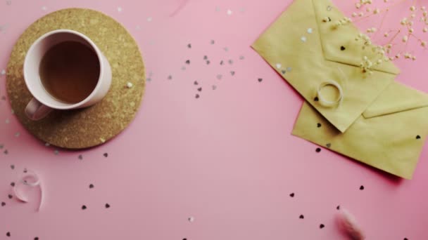 Manos de mujer moviendo un regalo de Navidad envuelto en un papel verde con lazo amarillo. Vista superior sobre tabla rosada de madera, posición plana — Vídeos de Stock