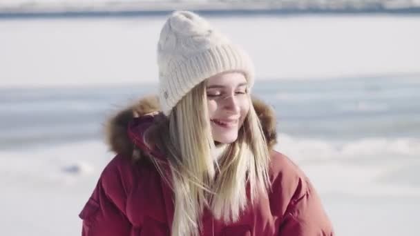 若いです女性で白いニット帽と赤い冬のジャケットポージングオンザカメラ — ストック動画