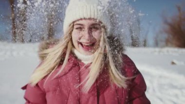 Beyaz örgü şapkalı ve kırmızı ceketli güzel kadın kar kusuyor.