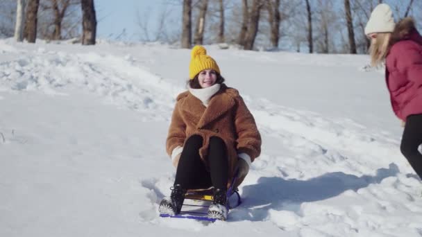 Dwie młode kobiety bawią się saniami w parku zimowym — Wideo stockowe