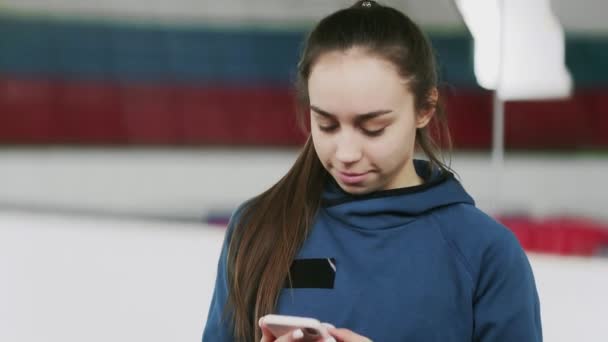 Mooie en jonge atletische vrouw neemt een selfie op smartphone in een sportschool of sportarena — Stockvideo