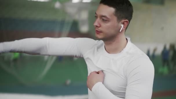 Boxeador masculino joven con auriculares inalámbricos se calientan antes del ejercicio deportivo — Vídeo de stock