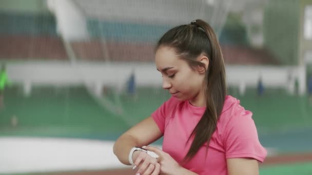 Jonge atleet meisje zet de timer op de klok en Stretchs — Stockvideo