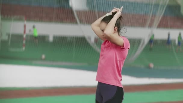 若い選手の女性は、スポーツ運動前に尾の中の髪を収集します。 — ストック動画