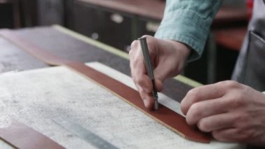Tanner kemerde delikler açıyor. Deri atölyedeki deri kemerin çalışma süreci. Adam el işi aleti tutuyor ve çalışıyor. Tanner eski tabakhanede..