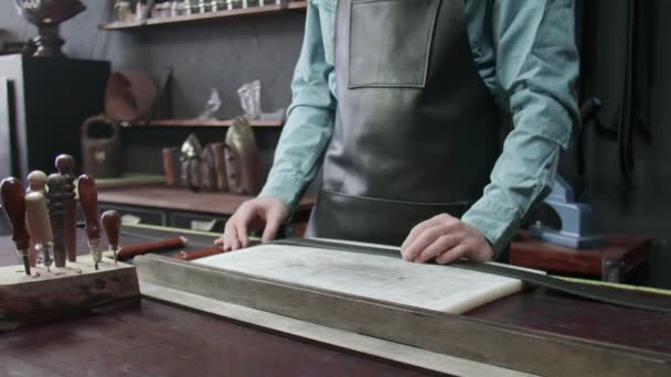 De tanner pakt een gereedschap voor het werken met leer. Veel verschillende gereedschappen voor handgemaakte. Metalen gereedschappen — Stockvideo