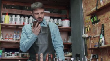 Erkek Tanner, arkadaşına aletler hakkında sesli mesaj kaydetmek için bir telefon kullanıyor.