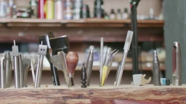 Outils de bronzage dans un support en bois. Processus de travail dans l'atelier de cuir . — Video