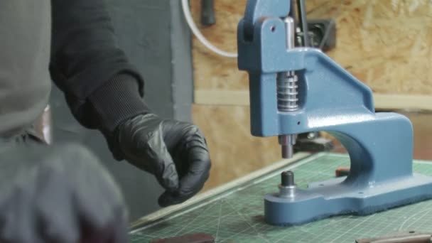人間のタンナーの閉鎖は、金属継手をインストールするためにプレスを使用しています。革工房での作業工程. — ストック動画