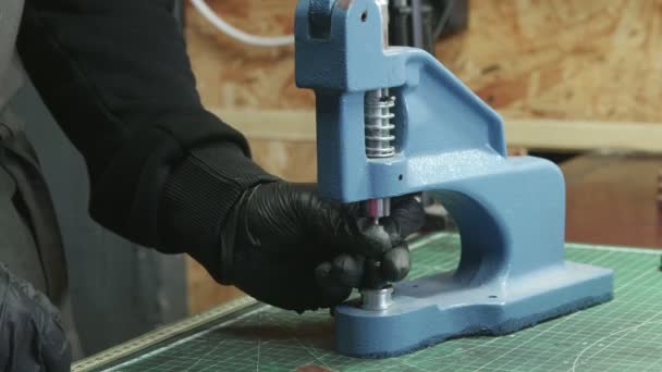 Gros plan de l'homme tanneur dans des gants noirs change la buse sur la presse. Processus de travail dans l'atelier de cuir .