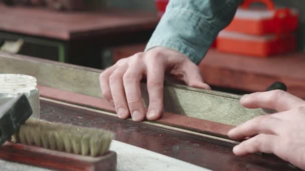 Detailní záběr profesionálního koželužského muže dává pastu na opasek v dílně. Pracovní proces koženého opasku v kožené dílně. — Stock video