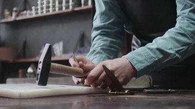 Profesyonel bronzlaştırıcı deri atölyesinde yeni kahverengi deri kemerde delikler açıyor. Deri atölyedeki deri kemerin çalışma süreci..