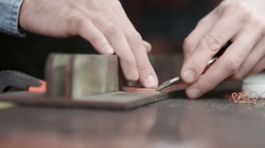 Deri bir zanaatkar kemerin kenarlarını kesiyor. Usta bir kenar içici araç kullanıyor.