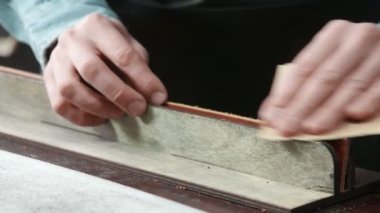 Bir zanaatkar kemerin kenarlarını keskinleştiriyor. Deri üstadı kemer yapıyor.