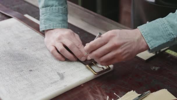Tanneuse professionnelle avec tablier fabriquant une nouvelle ceinture en cuir marron dans l'atelier de cuir. Processus de travail de la ceinture en cuir dans l'atelier de cuir . — Video