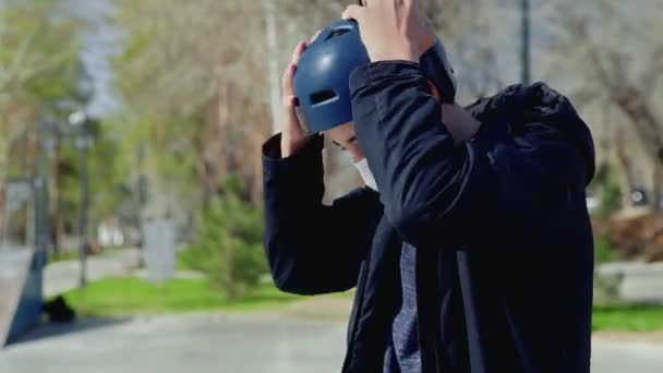 En ung bmx ryttare i medicinsk mask sitter på en cykel och bär hjälm — Stockvideo