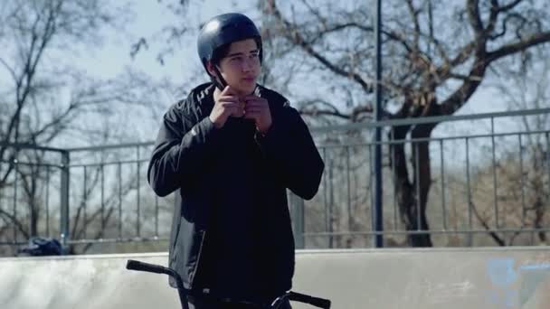 Um jovem bmx cavaleiro de pé e esperando por seus amigos no parque extremo — Vídeo de Stock