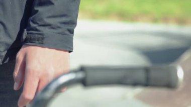 Tanımlanamayan ekstrem bmx motorcusu elinde bisikletle duruyor ve elini kol parmaklıklarına koyuyor.