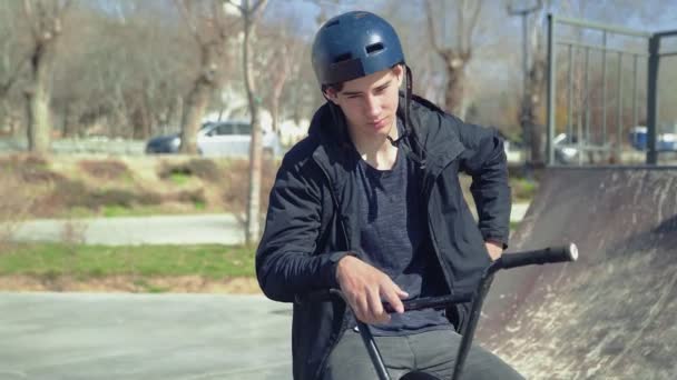 Ένας νεαρός αναβάτης BMX κάθεται σε ένα ποδήλατο και μιλάει στο τηλέφωνο Spartphone — Αρχείο Βίντεο