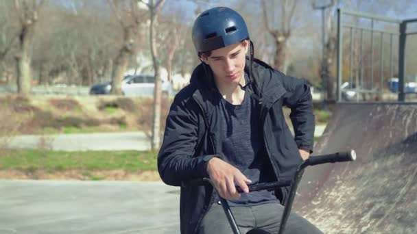 Un jeune coureur de bmx assis sur un vélo et parlant sur le spartphone — Video