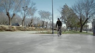 Genç bir BMX sürücüsü kaykay parkında boru numaraları yapıyor..