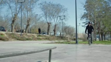 Genç bir BMX sürücüsü kaykay parkında boru numaraları yapıyor..