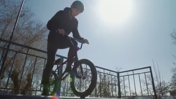 Un jinete bmx solo con capucha negra en rampas en el skatepark — Vídeos de Stock