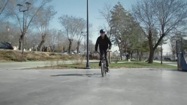 Un jeune bmx rider fait des tours sur pipe au skate park . — Video