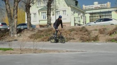 Genç bir bmx binicisi kaykay parkında boruların üzerinden döner..