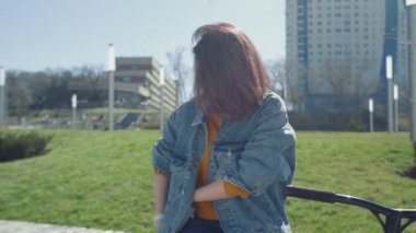 Genç Asyalı kadın bankta oturur ve yaz parkında akıllı telefon kullanır.