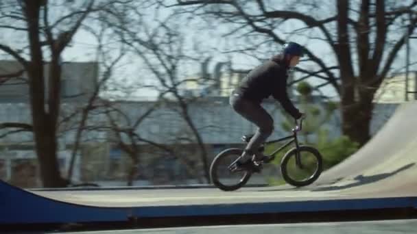 Jeździec bmx robi sztuczkę w skate parku o zachodzie słońca — Wideo stockowe