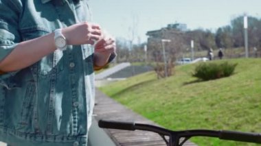 Tıbbi maskeli bir kadın motosikleti almadan önce ellerini sterilize ediyor.