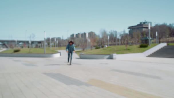 Jovem mulher asiática em uma jaqueta jeans monta uma scooter no parque de verão — Vídeo de Stock