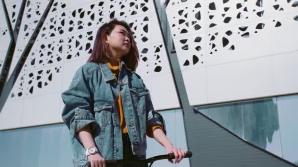 Jeune femme asiatique dans un jean veste avec le scooter ondulation avait à ses amis — Video