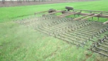 Bir traktörde tohum eken çiftçi tarlaya tahıl ekimi için toprağı hazırlıyor. Toz toprağına tohum ekiyorum. Bahar tarım işi. Hava görüntüsü, insansız hava aracı öne doğru uçar traktörü takip eder