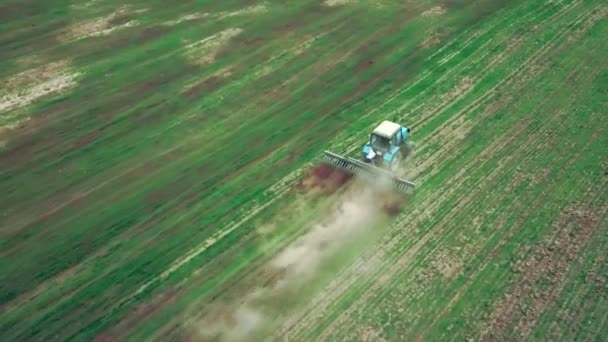 Vista aérea del tractor agrícola arando y pulverizando en el campo — Vídeo de stock