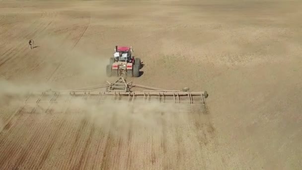 Flygfoto av en kraftfull energimättad traktor med en stor krokkraft, utför jordbearbetning för sådd av vintergrödor med en tallrikskultivator på hösten — Stockvideo