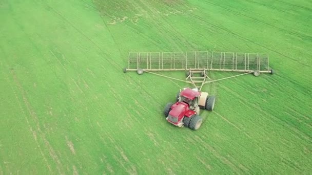 Fermier dans un tracteur avec un semoir prépare la terre pour semer des cultures céréalières dans le champ labouré. Planter des graines dans la poussière. Travaux agricoles de printemps. Vue aérienne du dessus, drone voler vers l'avant suivre tracteur — Video