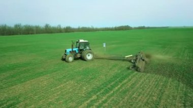 Bir traktörde tohum eken çiftçi tarlaya tahıl ekimi için toprağı hazırlıyor. Toz toprağına tohum ekiyorum. Bahar tarım işi. Hava görüntüsü, insansız hava aracı öne doğru uçar traktörü takip eder