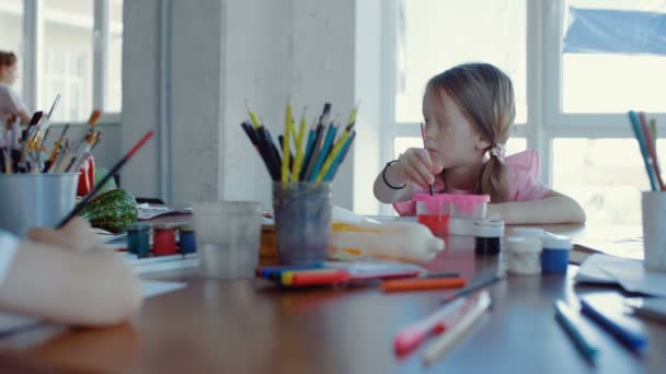 Aranyos lány rózsaszín ruhában rajzol az iskolában. — Stock videók